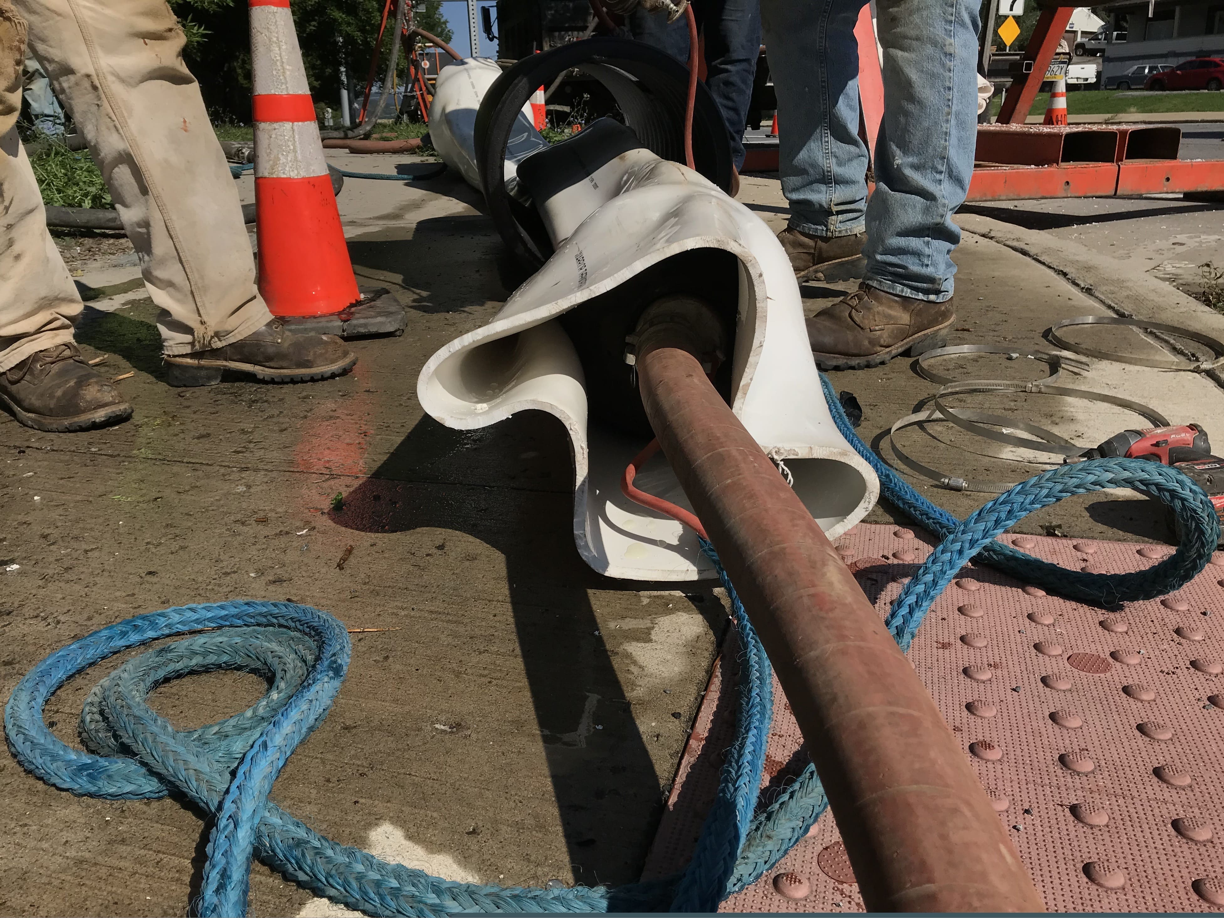 An image of a pipe inserted into the white PVC liner to heat up the liner to help bend the liner to get down the manhole.